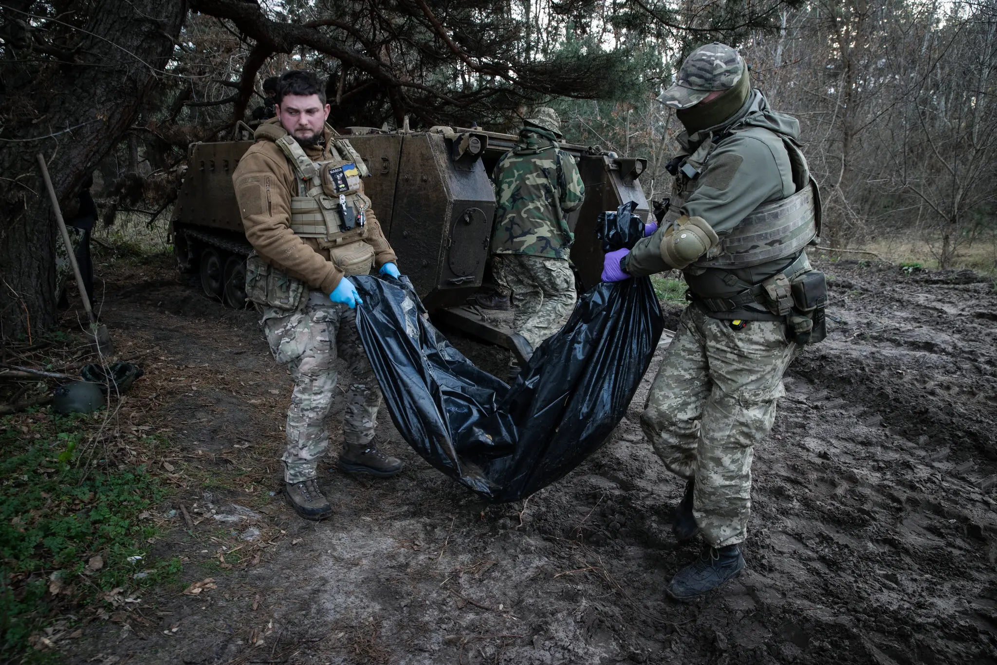 Переміщення тіл двох українських військових з бронетехніки у фургон для транспортування до моргу.